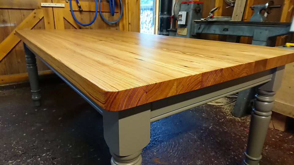 Made-to-order farmhouse table with a thick plank top and painted turned legs, in the workshop