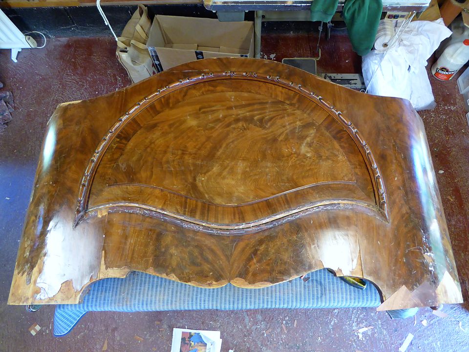 The same headboard before restoration, with lifting and missing veneer along the edges